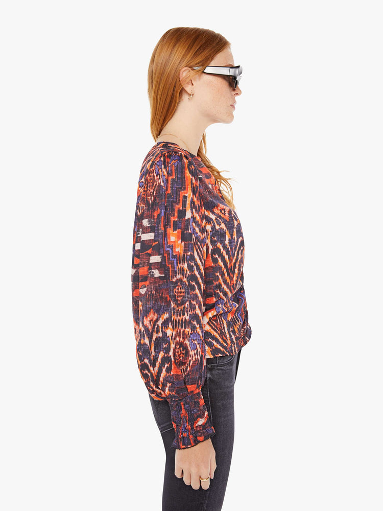 Side view of a womens blouse with a vibrant multi color print and balloon sleeves. 