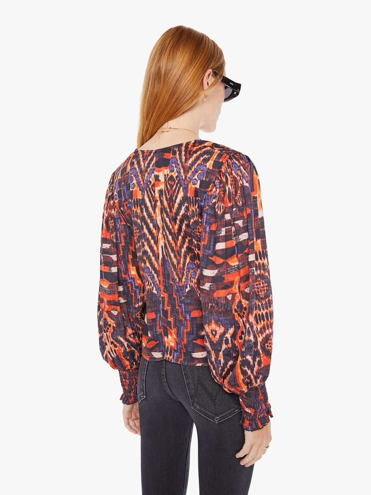 Back view of a womens blouse with a vibrant multi color print and balloon sleeves. 