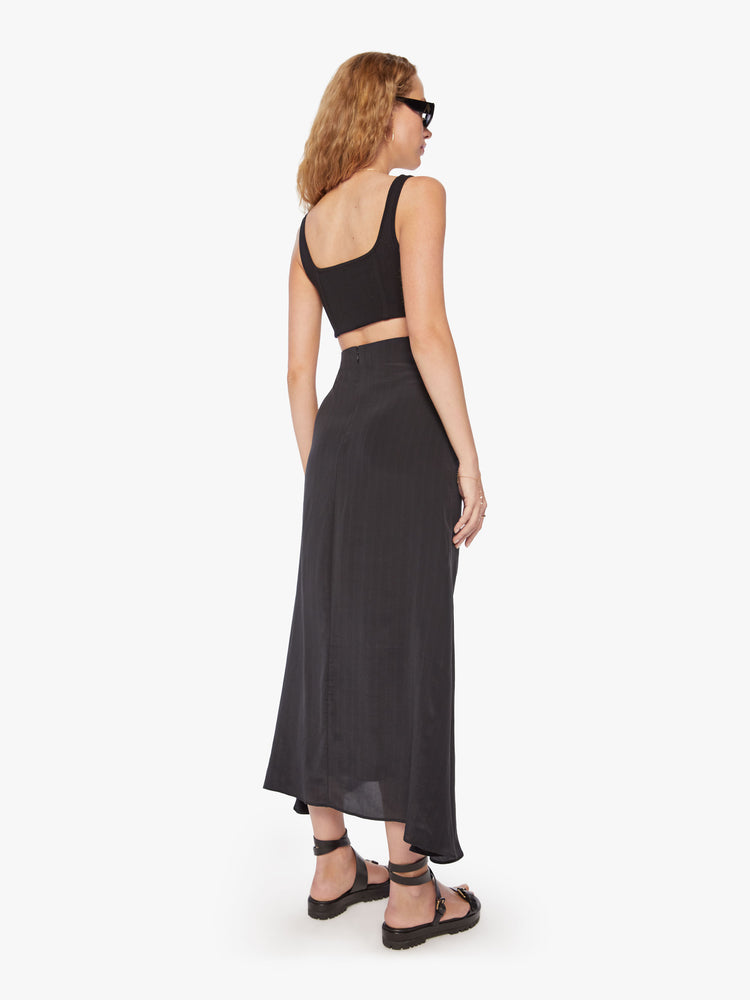 Back view of a woman maxi skirt in bold prints and modern neutrals with a high rise, gathered seam down the front and a flowy fit that hits at the ankle.