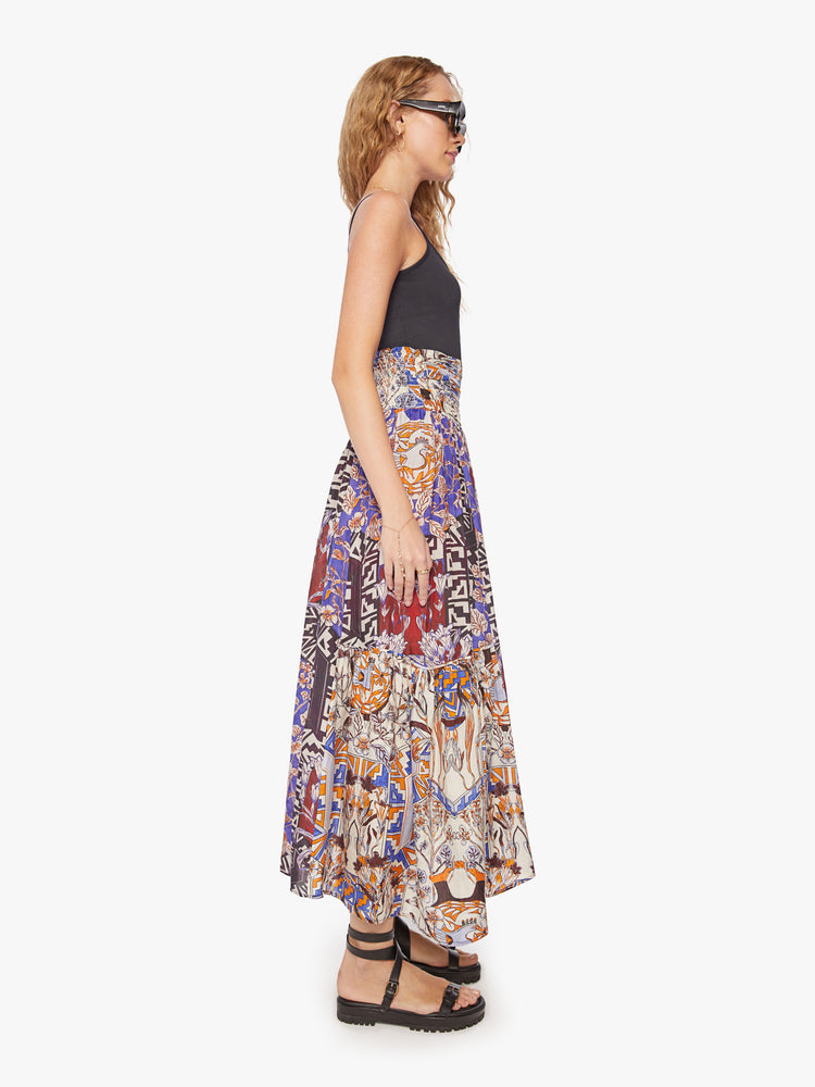 Side view of a woman maxi skirt in bold prints and modern neutrals, with a super high rise, tiered skirt, uneven hem and a flowy fit.