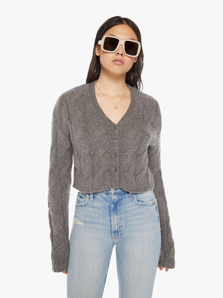Front view of a woman dark grey hue with cable knit details cropped sweater designed with a V-neck, buttons down the front and a slim, cropped fit.