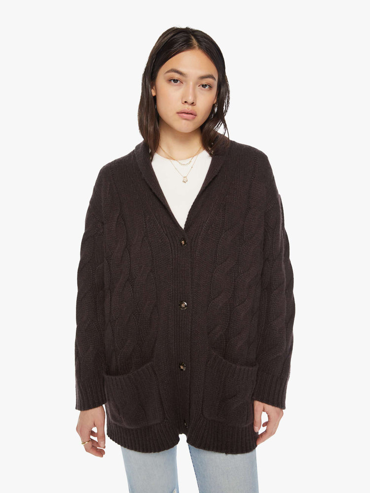 Front view of a woman brown oak hue oversized cardigan designed with a shawl collar, front patch pockets, buttons down the front, and a boxy, oversized fit.