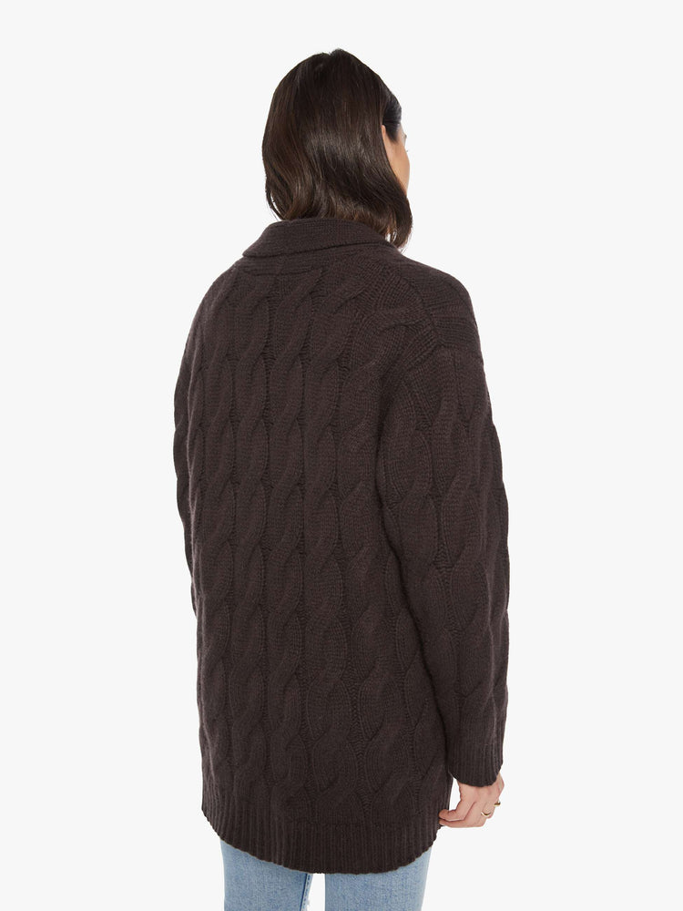 Back view of a woman brown oak hue oversized cardigan designed with a shawl collar, front patch pockets, buttons down the front, and a boxy, oversized fit.