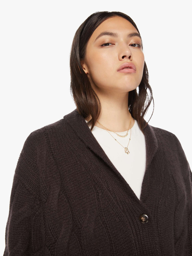 Close up view of a woman brown oak hue oversized cardigan designed with a shawl collar, front patch pockets, buttons down the front, and a boxy, oversized fit.