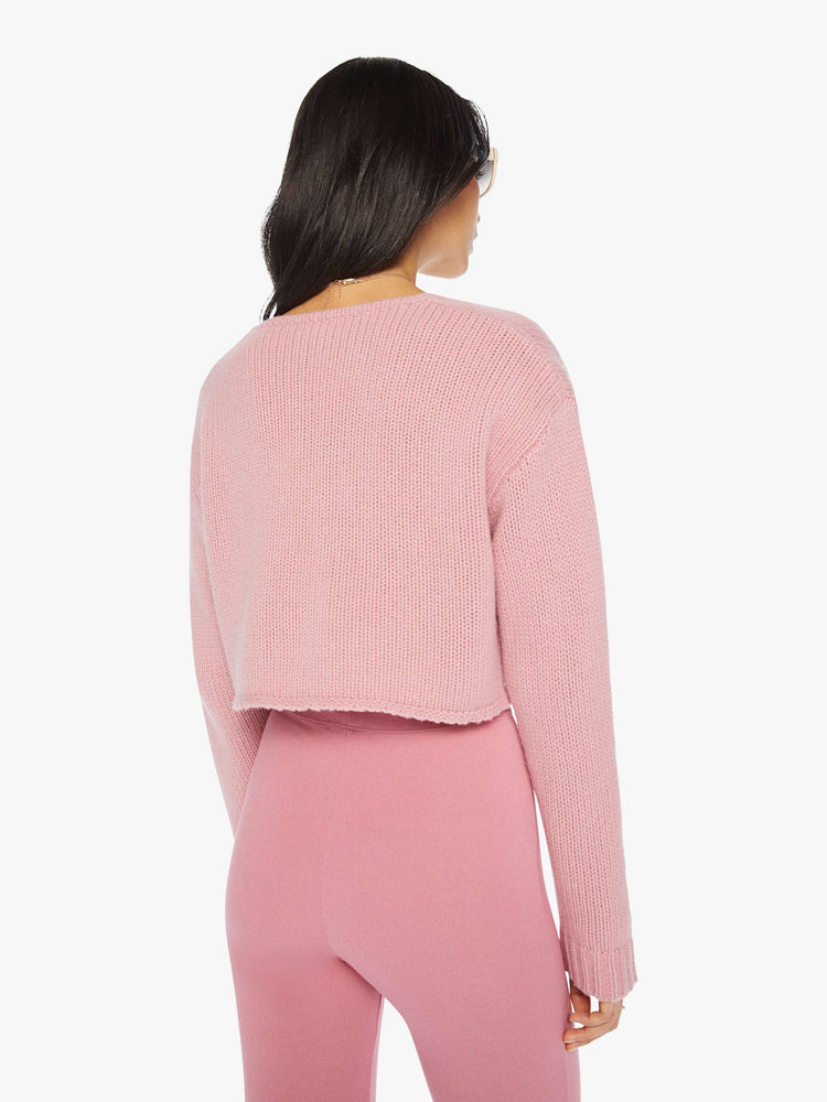 Back view of a woman pink cropped sweater with a V-neck, buttons down the front, drop shoulders and a cropped fit.