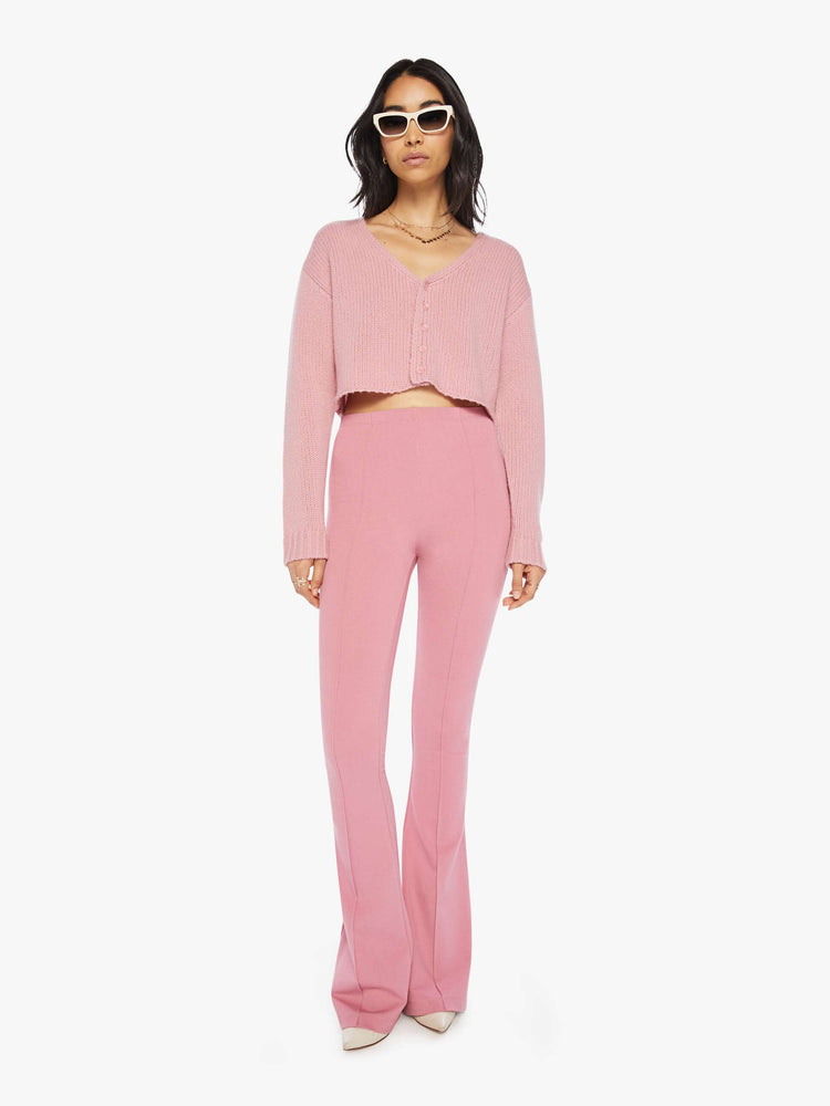Full body view of a woman pink cropped sweater with a V-neck, buttons down the front, drop shoulders and a cropped fit.