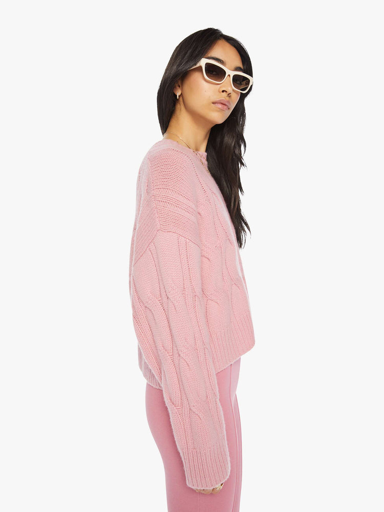 Side view of a woman pink knit sweater with crew neck, drop shoulders, extra-long sleeves and a loose fit.