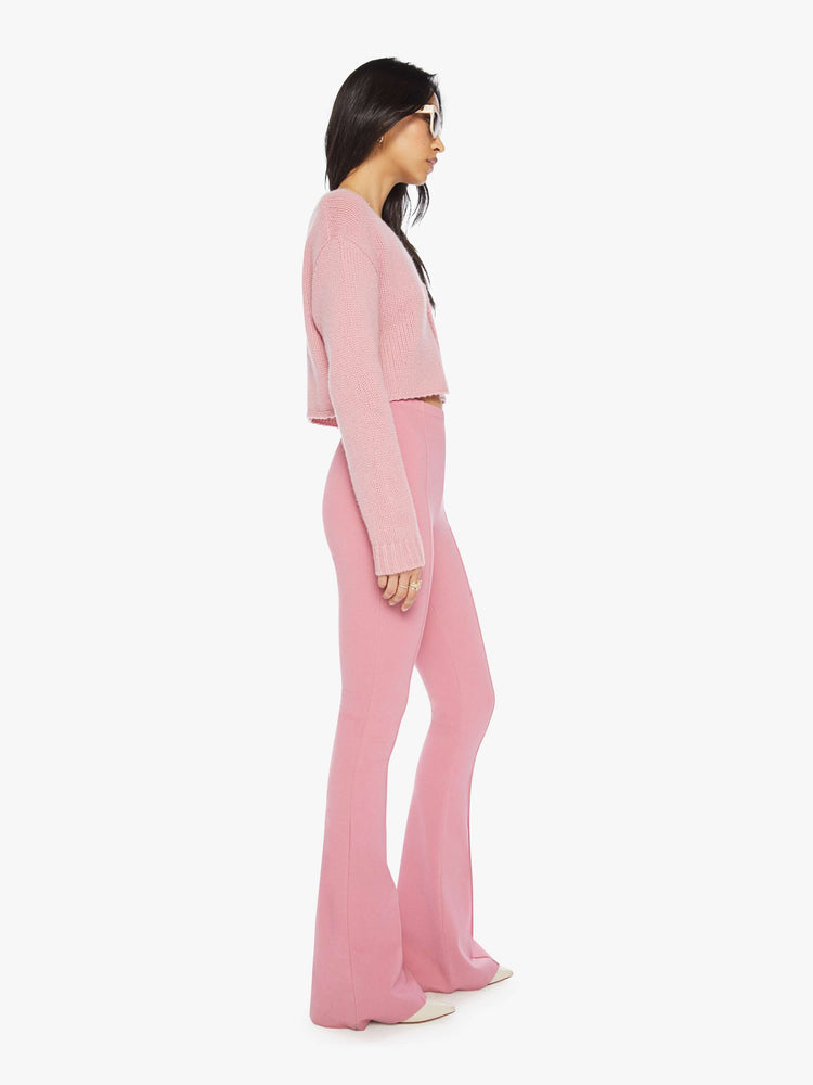 Side view of woman pink flared legging with a high rise, flared leg, long inseam and a pintuck detail down the front of each leg.