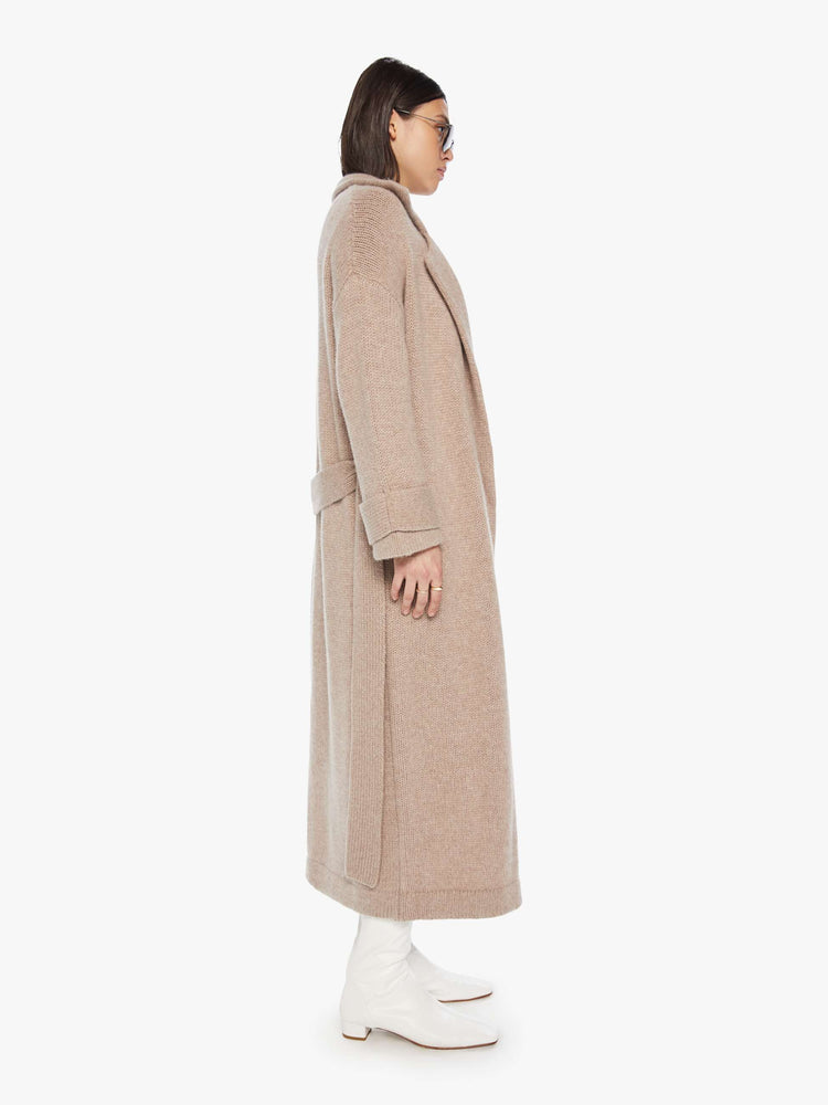 Side view of a woman toast colored oversized coat with a notched collar, drop shoulders, a tied waist and a calf-length hem.