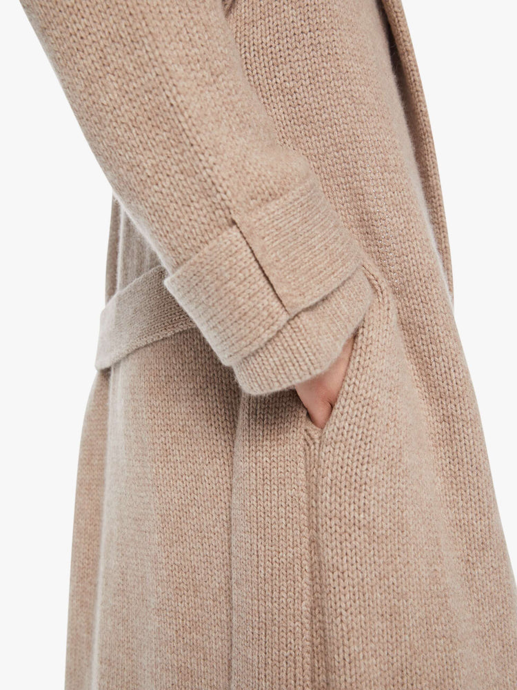 Arm hem view of a woman toast colored oversized coat with a notched collar, drop shoulders, a tied waist and a calf-length hem.