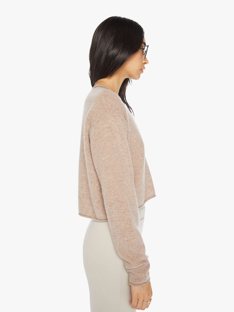 Side view of a woman toast colored sweater with a crewneck, drop shoulders, stacked long sleeves and a cropped hem.