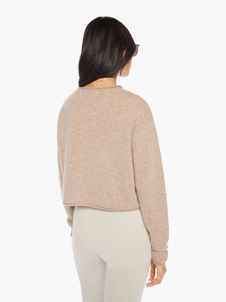 Back view of a woman toast colored sweater with a crewneck, drop shoulders, stacked long sleeves and a cropped hem.