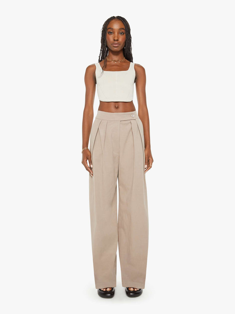 Front  view of woman brown hue pants are designed with a buttoned waistband, front pleats, side slit pockets and a wide leg.