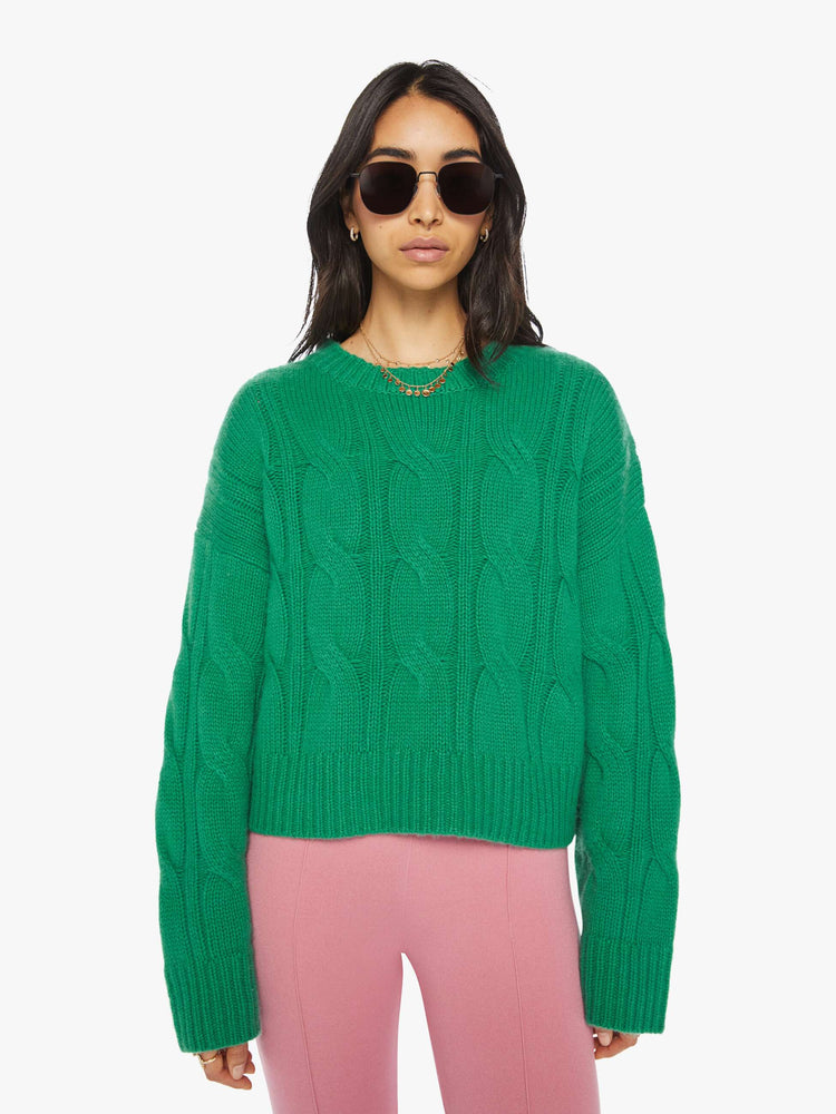 Front view of a woman green knit sweater with  a crew neck, drop shoulders, extra-long sleeves and a loose fit.