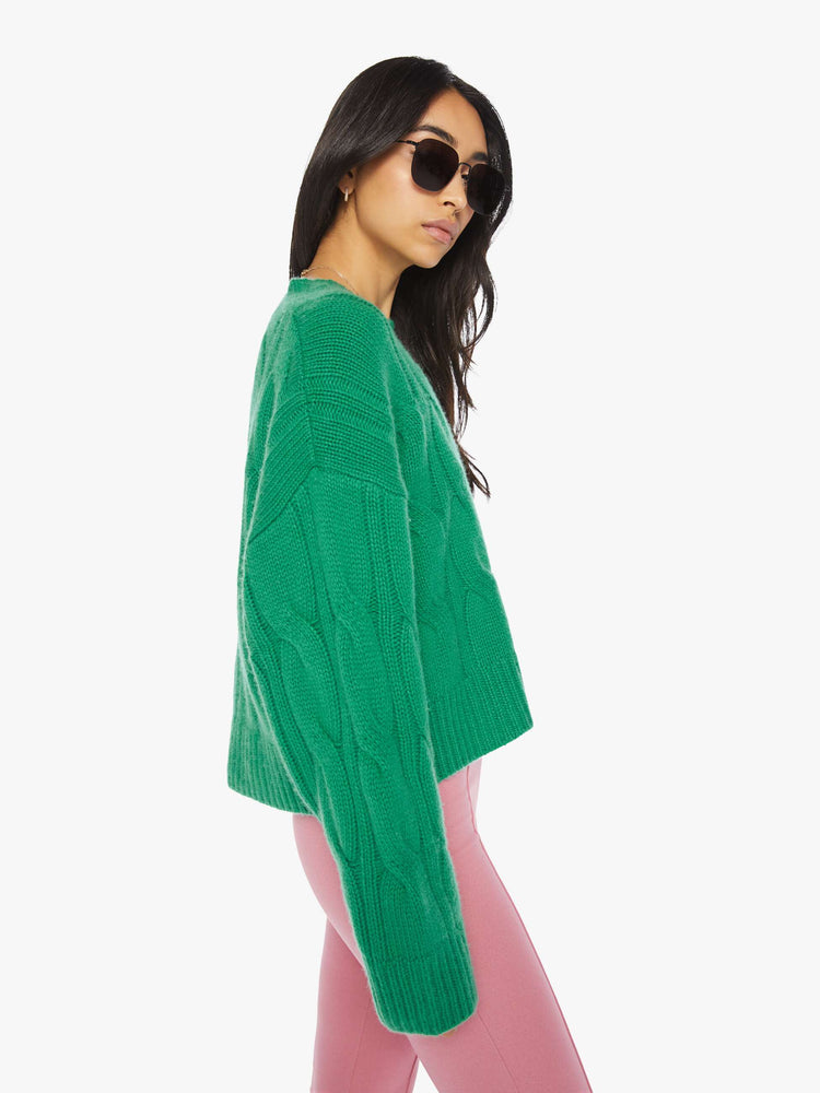Side view of a woman green knit sweater with a crew neck, drop shoulders, extra-long sleeves and a loose fit.