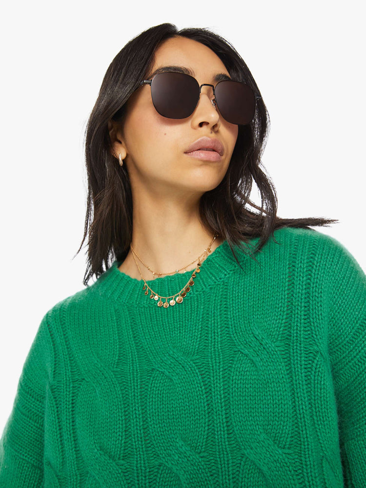 Close up view of a woman green knit sweater with a crew neck, drop shoulders, extra-long sleeves and a loose fit.