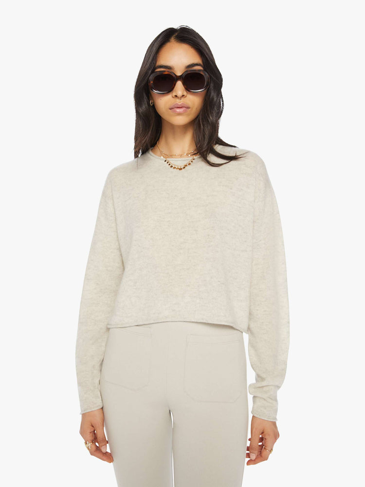 Front view of a woman off white sweater with a crewneck, drop shoulders, stacked long sleeves and a cropped hem.