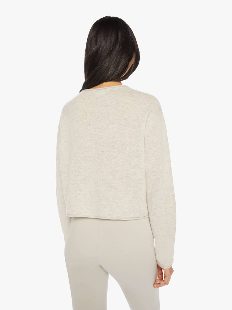 Back view of a woman off white sweater with a crewneck, drop shoulders, stacked long sleeves and a cropped hem.