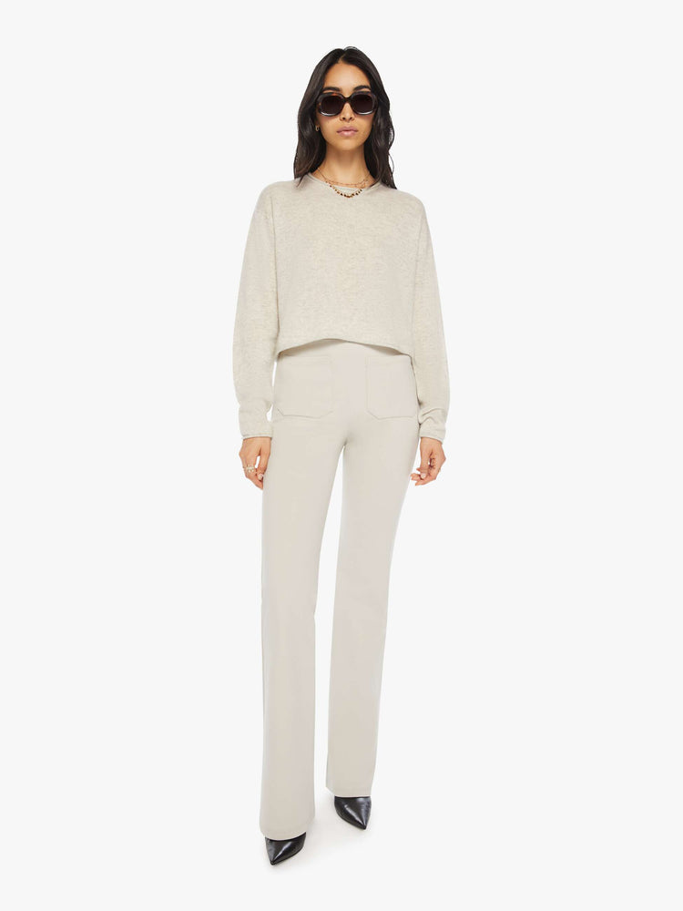 Full body view of a woman off white sweater with a crewneck, drop shoulders, stacked long sleeves and a cropped hem.
