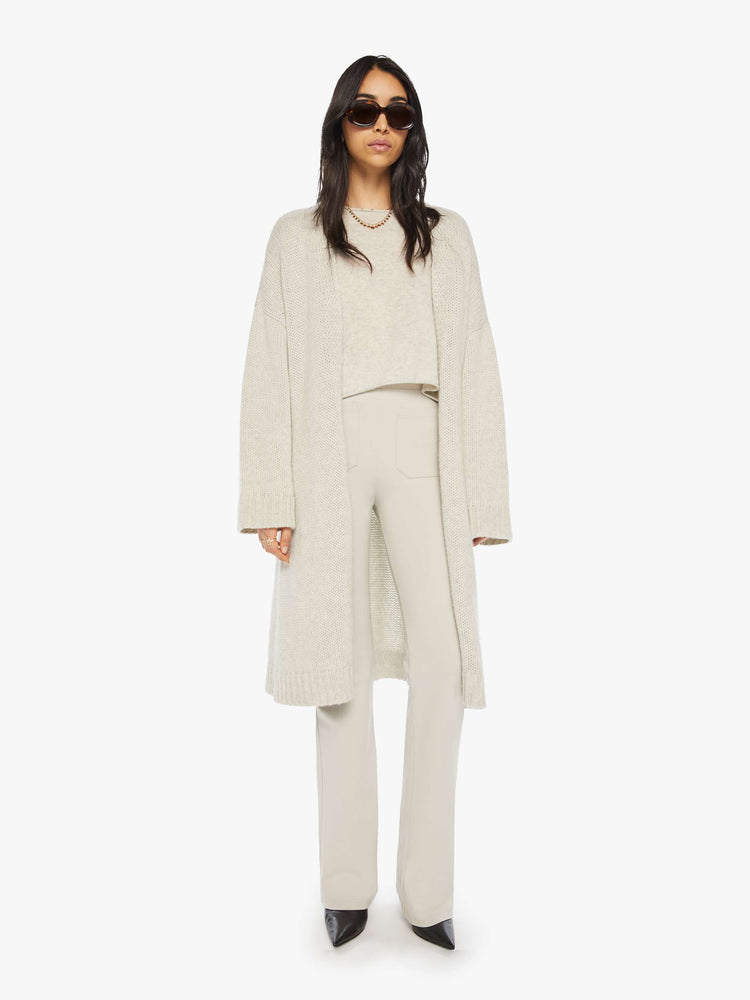 Front view of woman in off white oversized cardigan with an open front, shawl collar and a knee-length hem.