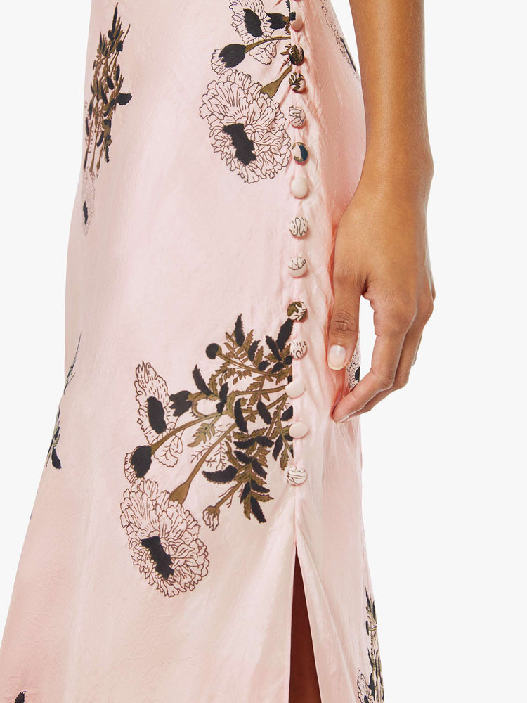 Side close up view of a womens pink silk dress featuring a floral print and ankle length hem..