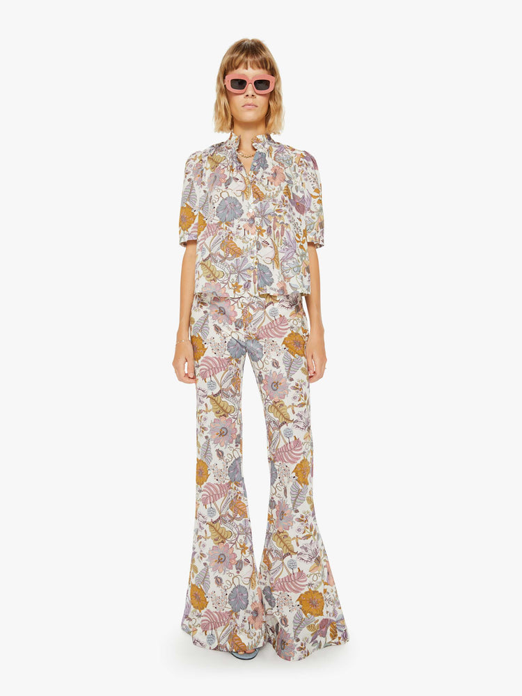 Front view of a woman colorful floral print, and feature a high rise, flared leg and a long inseam.