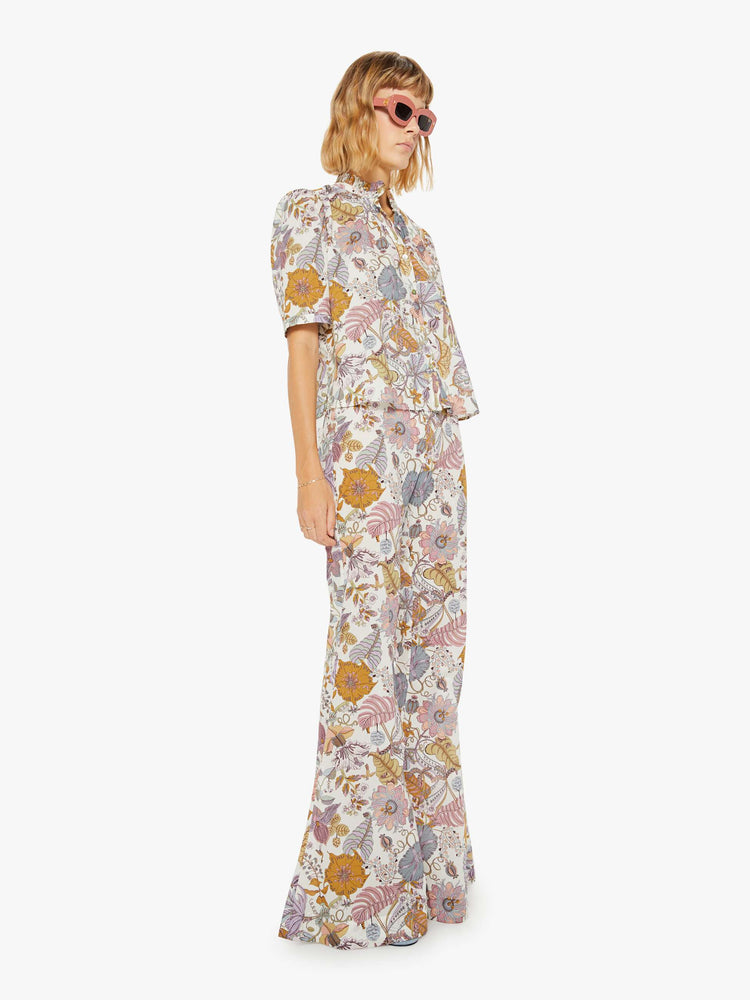 Side angle view of a woman colorful floral print, and feature a high rise, flared leg and a long inseam.