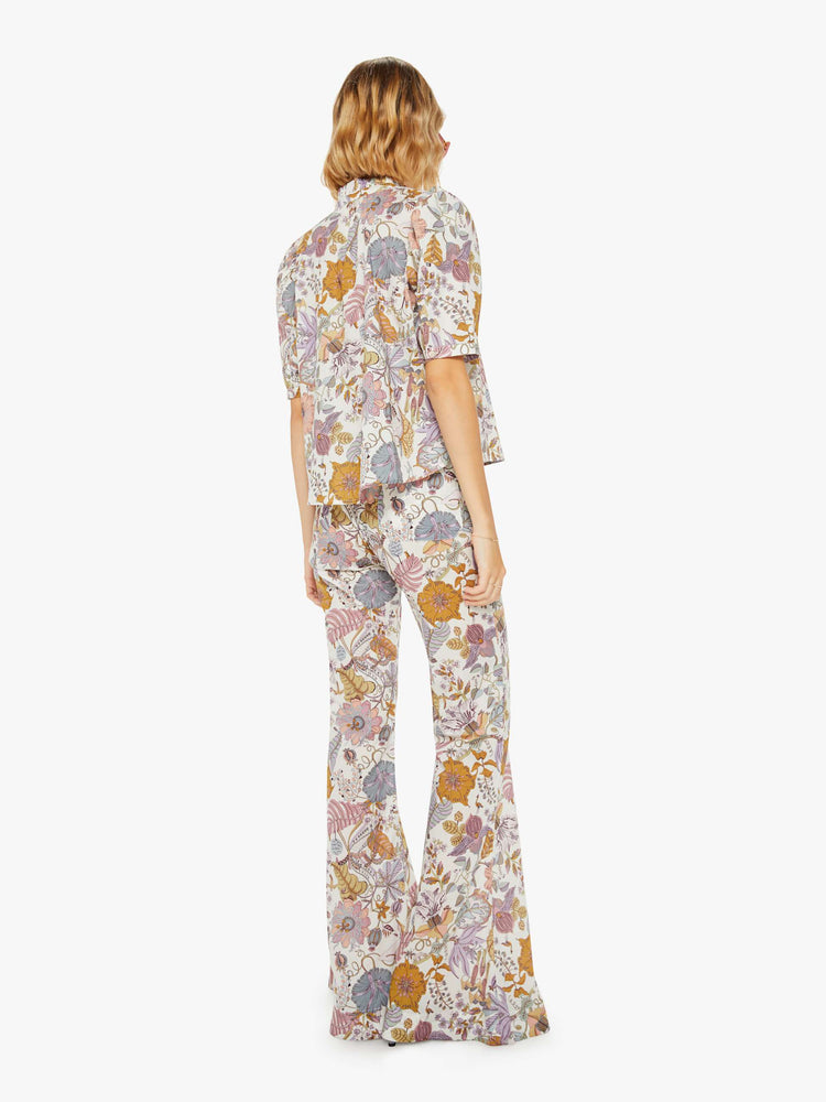 Back view of a woman colorful floral print, and feature a high rise, flared leg and a long inseam.