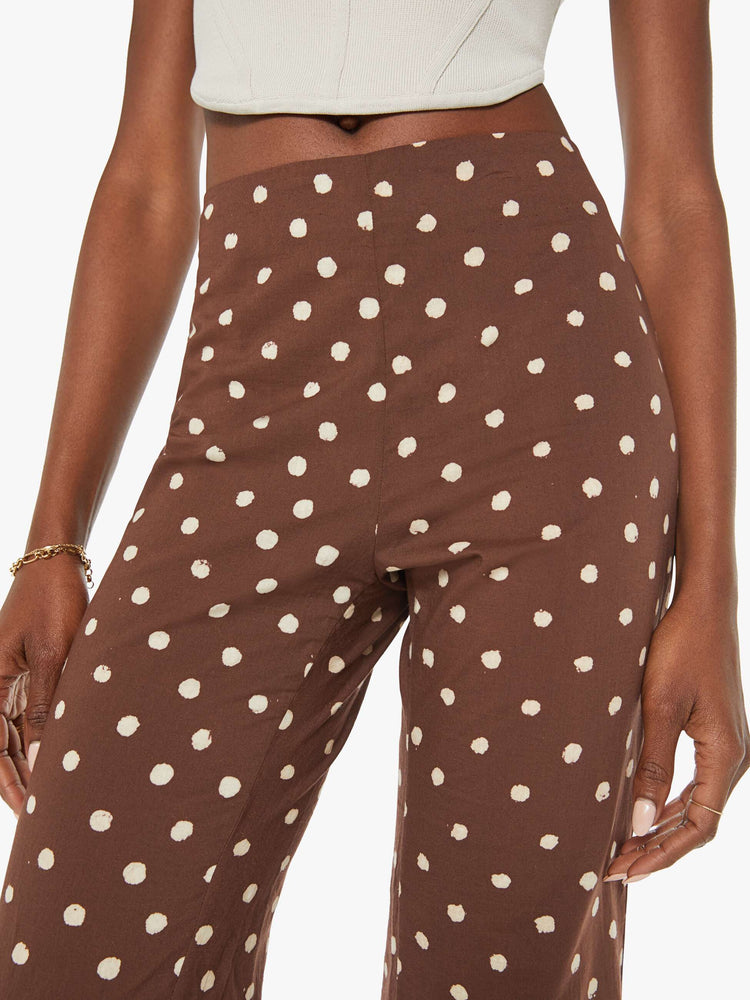 Close up view of a woman brown with white polka dots, and feature a high rise, flared leg and a long inseam.