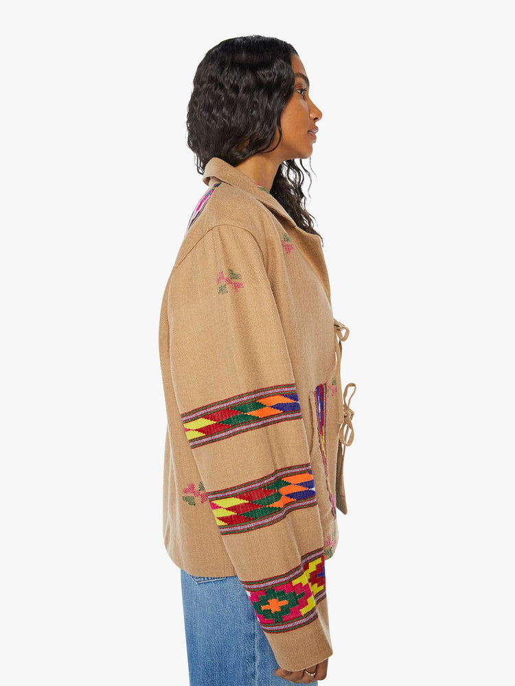 Side view of a woman Western blanket patchwork and fringe details Jacket, and features a notched collar, drop shoulders, patch pockets and a tie closure.