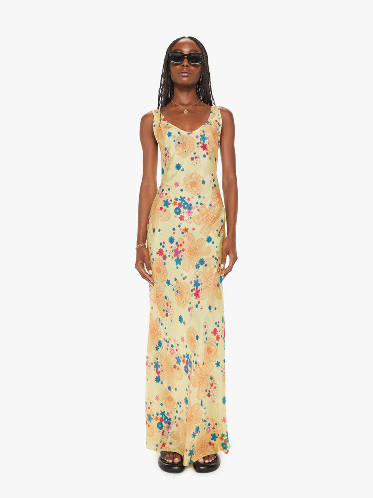 Front view of a woman pastel yellow with a colorful floral print, and features a scoop neck, narrow fit and an ankle-length hem.