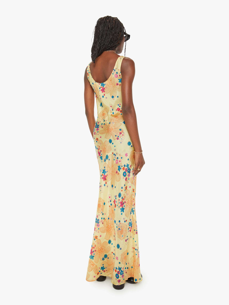 Back view of a woman pastel yellow with a colorful floral print, and features a scoop neck, narrow fit and an ankle-length hem.