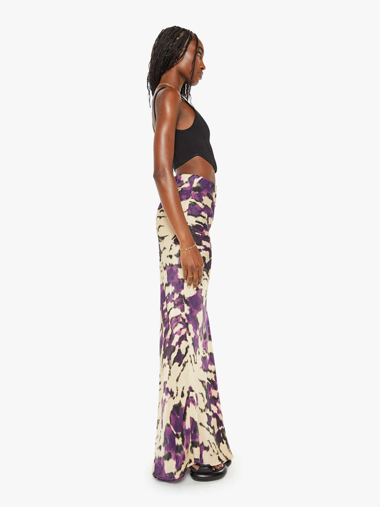 Side view of a woman violet and cream abstract print kirt features a high rise, slim fit and long hem.