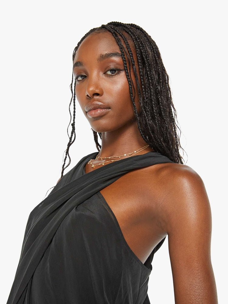 Close up view of a woman black dress with a wrapped halter neck, gathered seam down the front and a long ankle-length hem.
