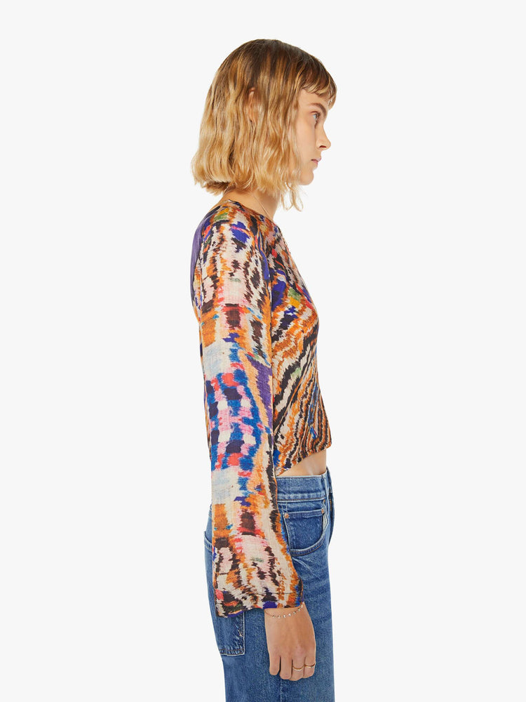 Side view of a woman colorful abstract print top with crew neck, long sleeves and a slightly cropped hem.