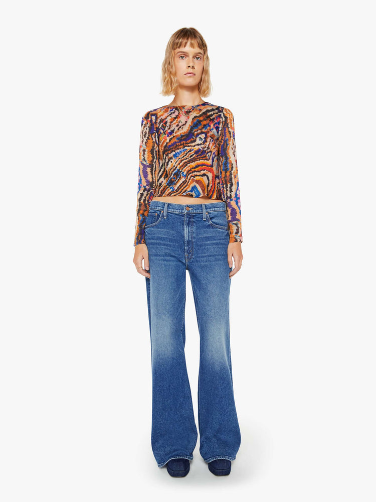 Full body view of a woman colorful abstract print top with crew neck, long sleeves and a slightly cropped hem.