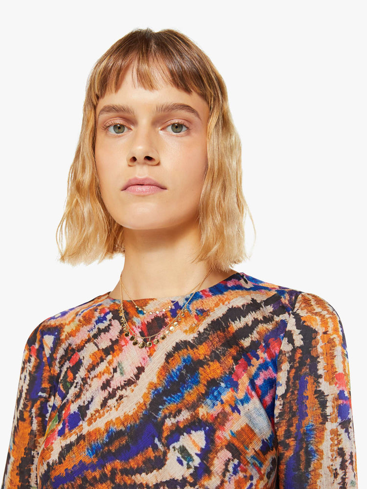 Close up view of a woman colorful abstract print top with crew neck, long sleeves and a slightly cropped hem.