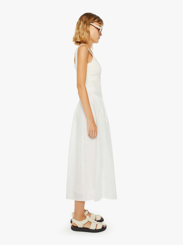 Side view of a woman off white skirt with a super high rise, tiered skirt, uneven hem and a flowy fit.