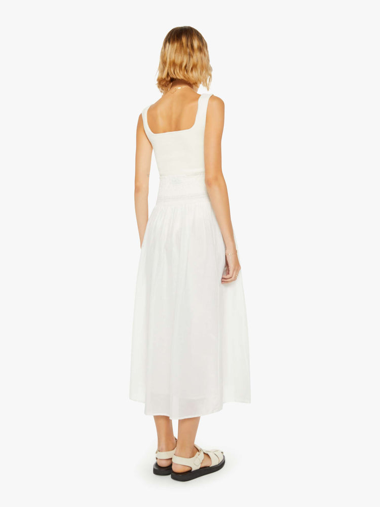 Back view of a woman off white skirt with a super high rise, tiered skirt, uneven hem and a flowy fit.