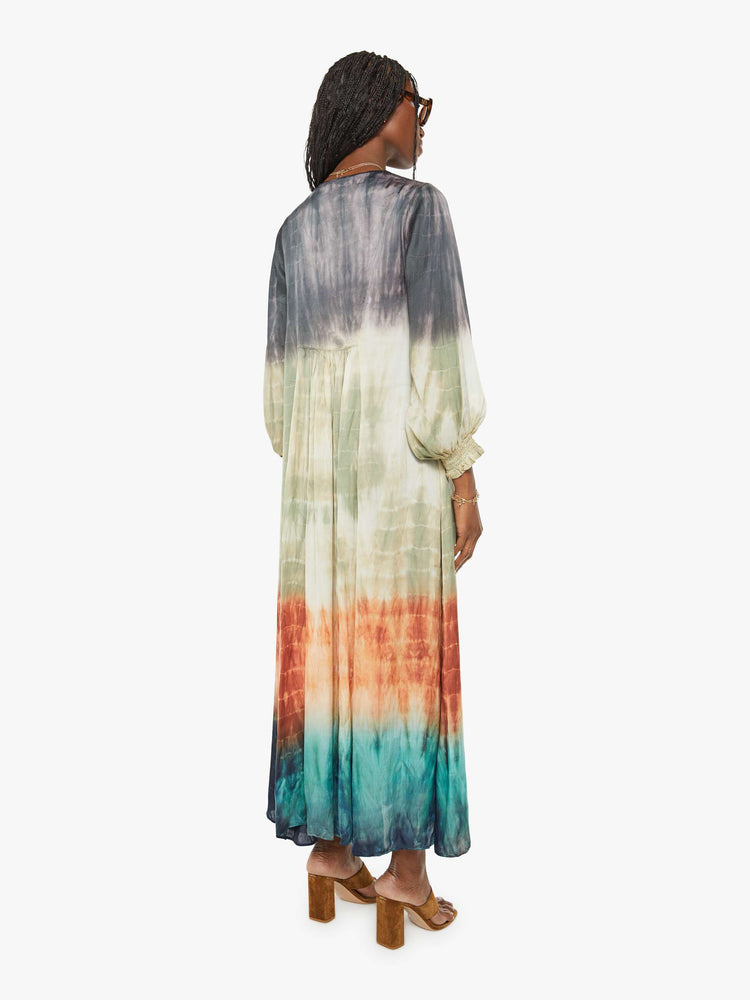Back view of a woman maxi dress with a V-neck, cropped balloon sleeves and a loose, flowy fit in grey, green, orange, and blue ombre.