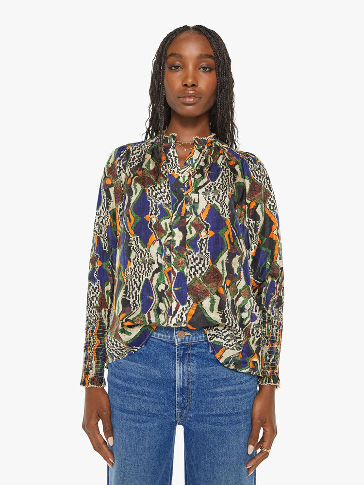 Front view of a woman in a bright graphic print long sleeve blouse features a deep V-neck, balloon sleeves with thick gathered hems and a loose, flowy fit.
