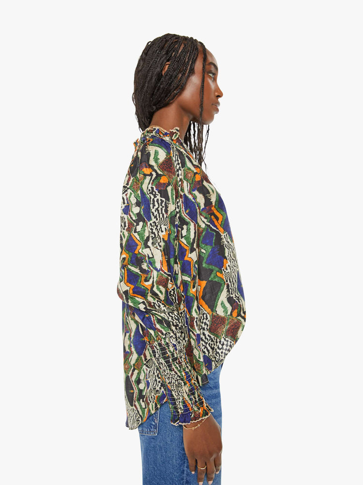 Side view of a woman in a bright graphic print long sleeve blouse features a deep V-neck, balloon sleeves with thick gathered hems and a loose, flowy fit.