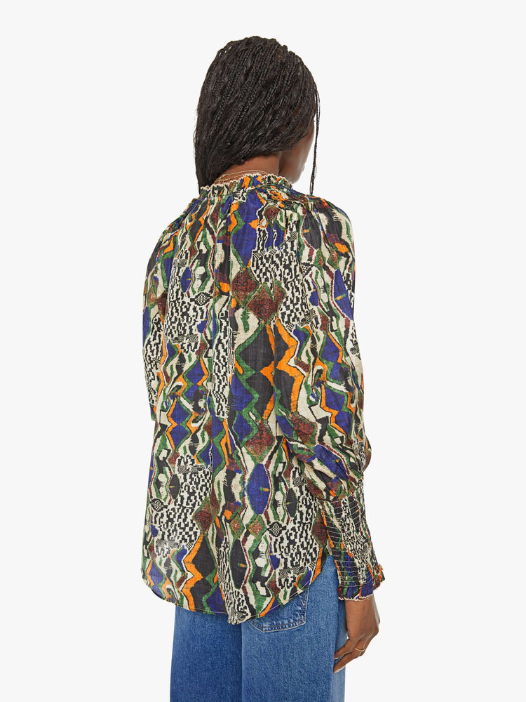 Back view of a woman in a bright graphic print long sleeve blouse features a deep V-neck, balloon sleeves with thick gathered hems and a loose, flowy fit.