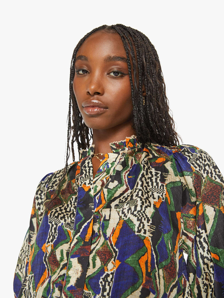 Close up view of a woman in a bright graphic print long sleeve blouse features a deep V-neck, balloon sleeves with thick gathered hems and a loose, flowy fit.