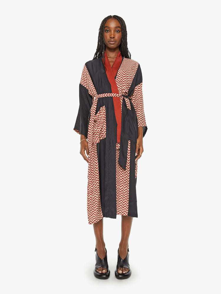 Front view of a woman robe with colorblocked silk in black and a red-and-white zig zag print, and features drop shoulders, a calf-length hem and a loose, flowy fit.