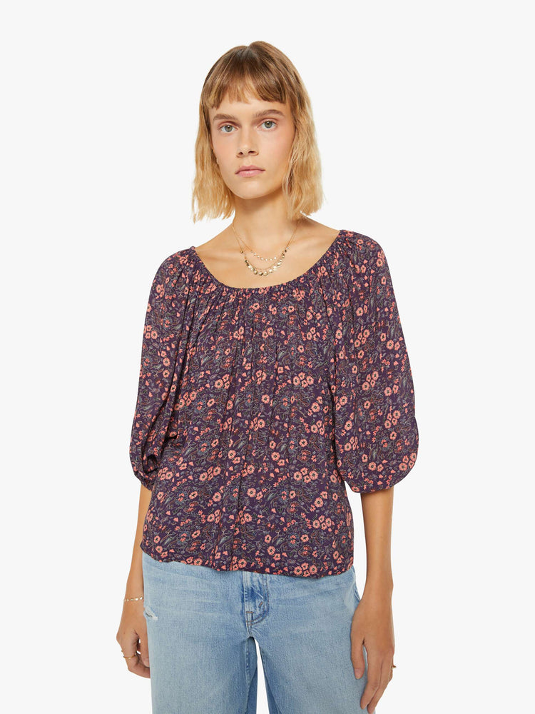 Front view of a woman blouse  in a purple and pink floral print and features an elastic boat neck that can be worn off-the-shoulder, 3/4-length balloon sleeves and a flowy fit.