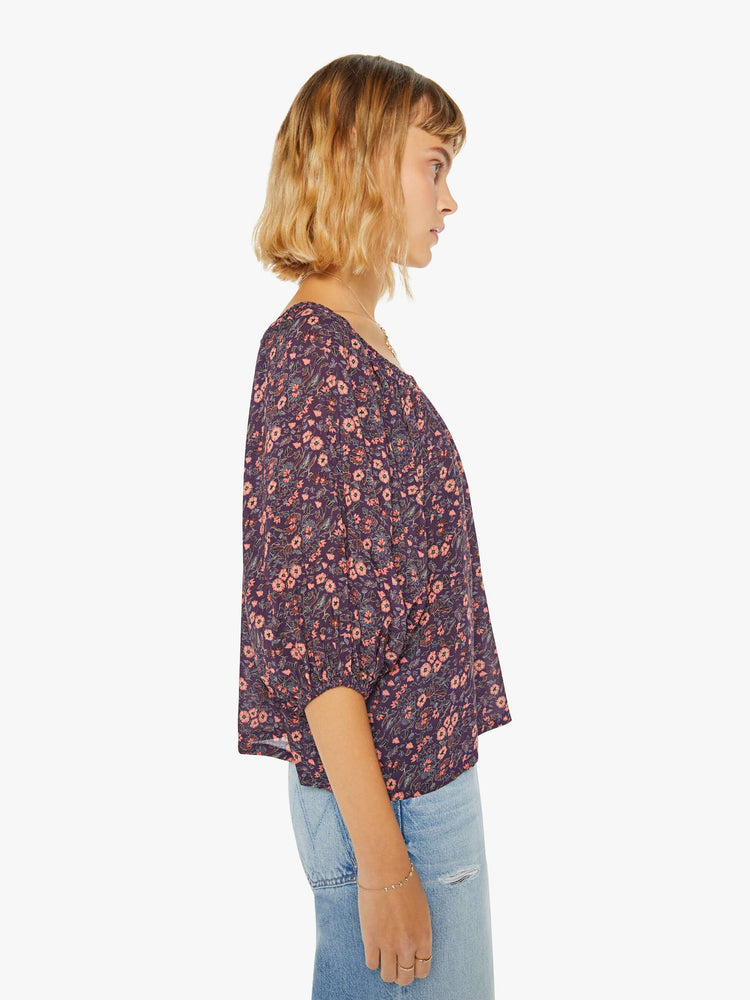 Side view of a woman blouse in a purple and pink floral print and features an elastic boat neck that can be worn off-the-shoulder, 3/4-length balloon sleeves and a flowy fit.