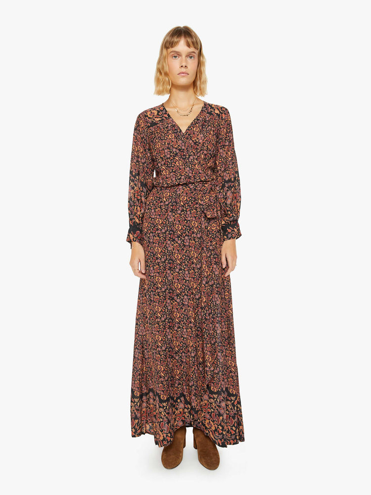 Front view of woman long sleeve dress in a warm tone floral print, and features a V-neck, tied waist and long maxi skirt with a loose, flowy fit.