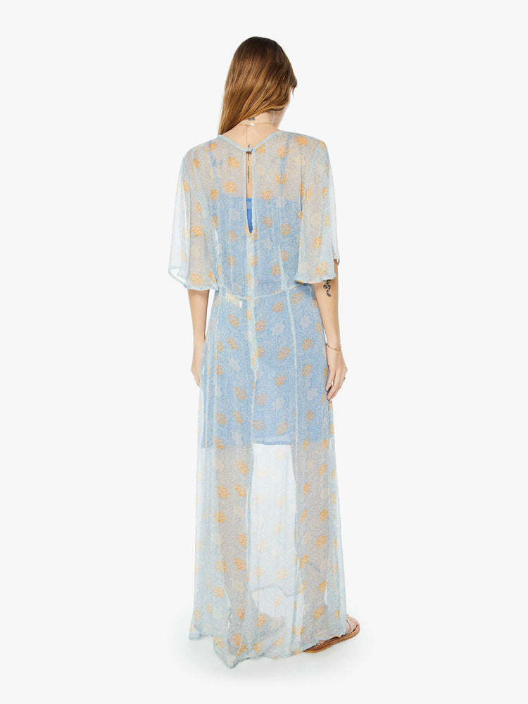 Back view of a womens sheer dress in a light blue and orange floral print featuring front slits and a blue slip.