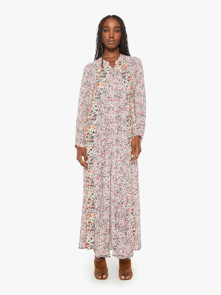 Front view of a woman  in white with a multi-color floral print, this maxi dress is designed with voluminous sleeves and has an A-line cut for a loose, breezy feel.